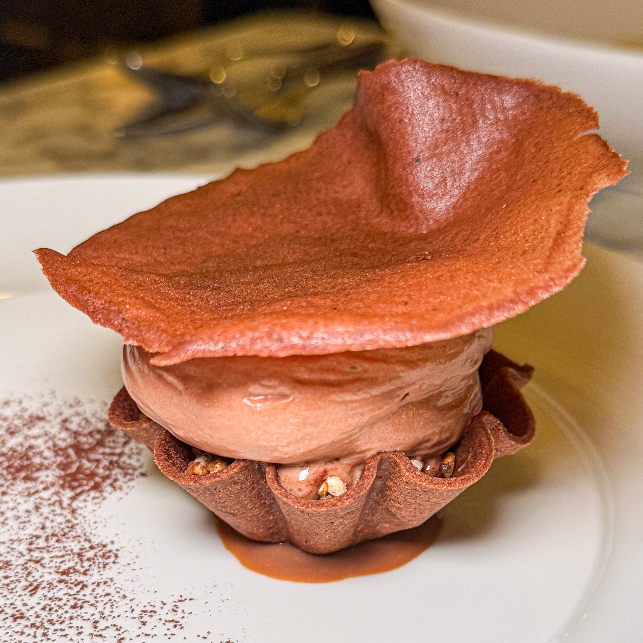 Chocolate mousse in a chocolate tuile cup, capped with a thin chocolate wafer, in caramel